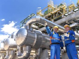 teamwork: group of industrial workers in a refinery - oil processing equipment and machinery